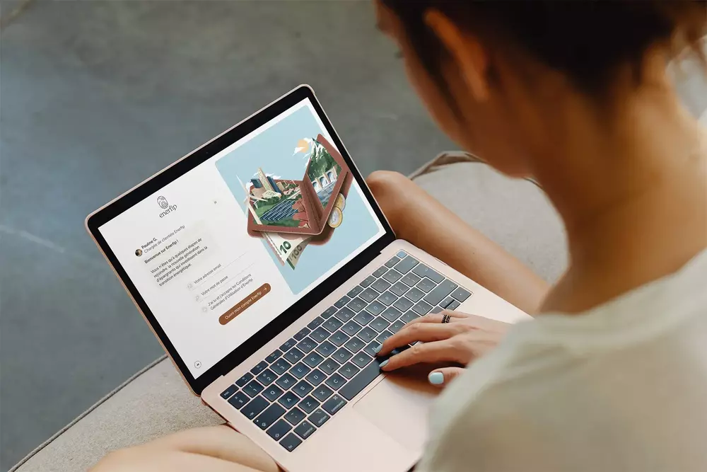 Person using a laptop showing the Enerfip platform with a graphic of a wallet and euro banknotes and coins on screen.