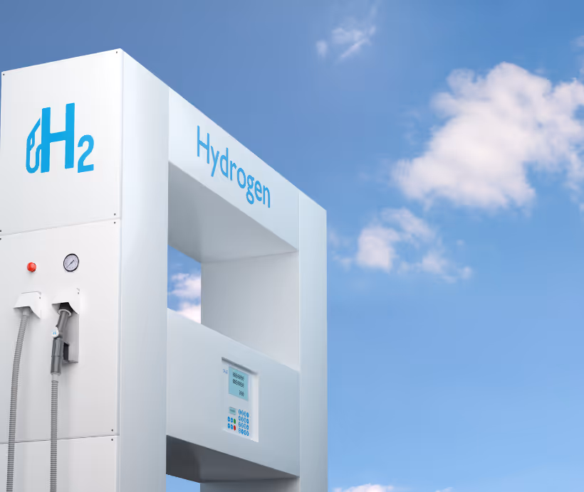 Modern white hydrogen fuel pump with H2 symbol and blue sky with clouds in the background.