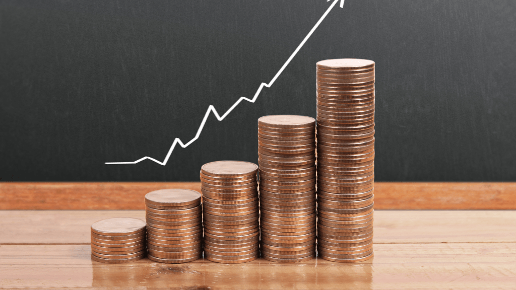 Coins stacked in increasing columns symbolizing financial growth, with an upward trending graph in the background.