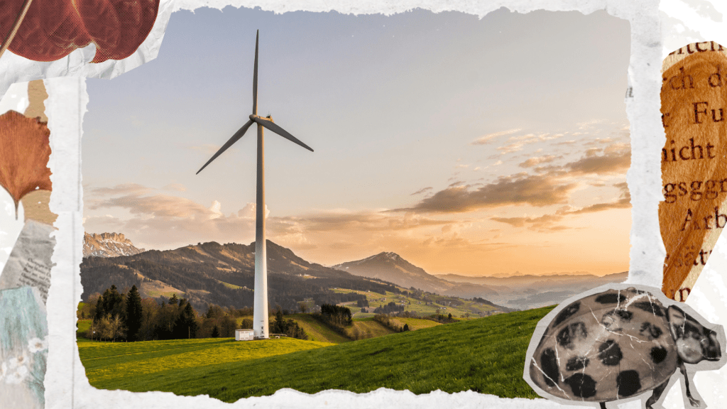 A wind turbine stands on a green landscape with mountains in the background and a partly cloudy sky.