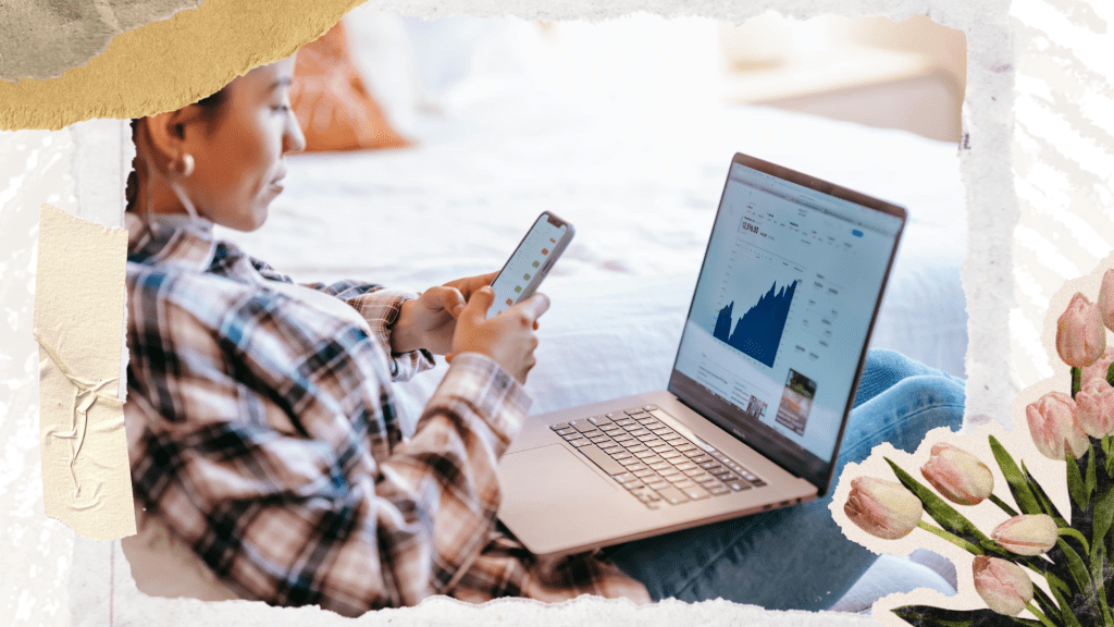 A person sitting on a bed, using a mobile phone and a laptop displaying financial charts.