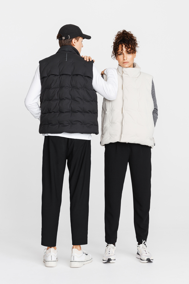 Man in black cap and vest with his back to the camera, holding the shoulder of a woman in a white vest, both wearing black pants and white sneakers. Decathlon Style Sportswear Athleisure Laure Mimram