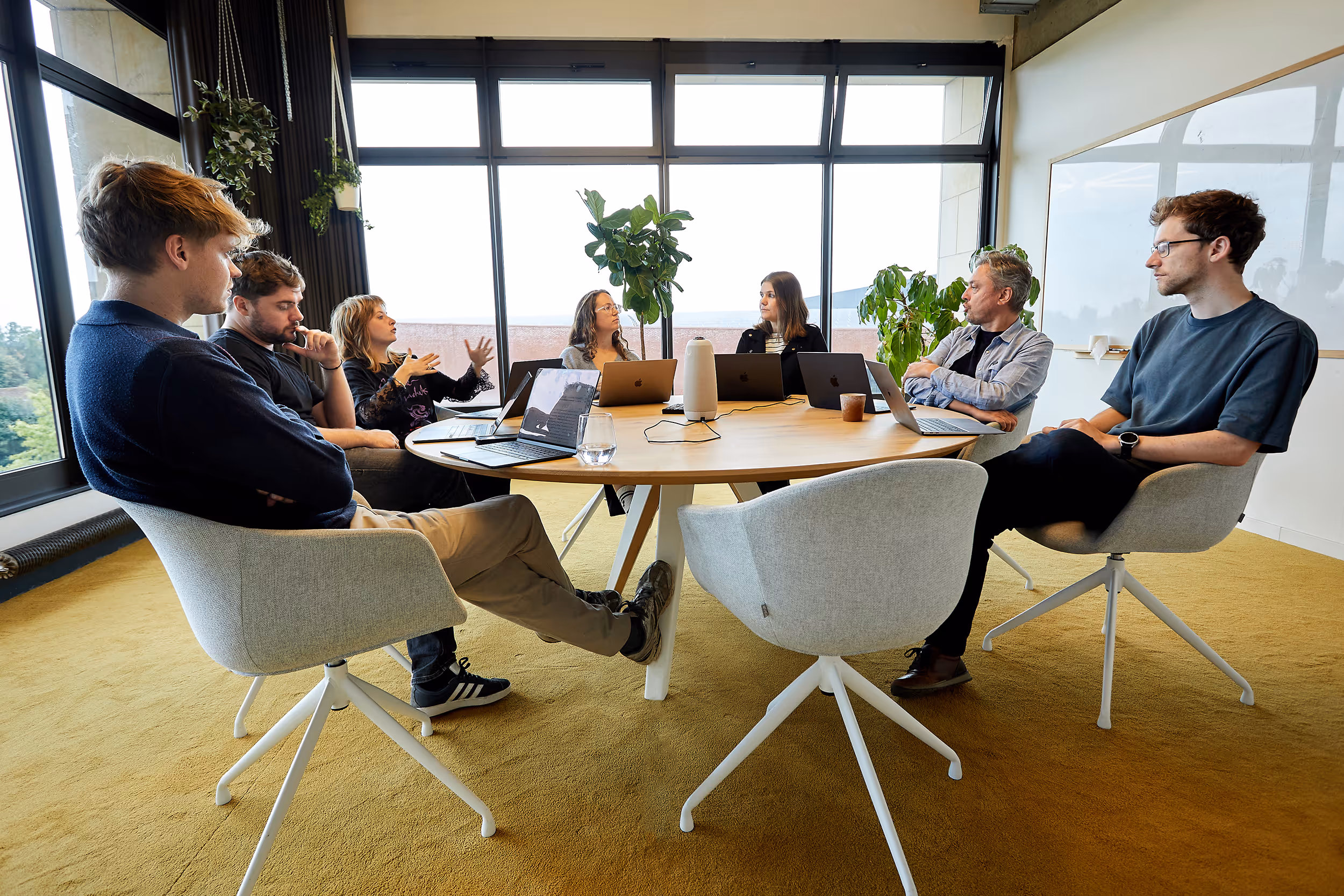 Medewerkers van ticketmatic bespreken samen ideeën tijdens een vergadering aan een ronde tafel.