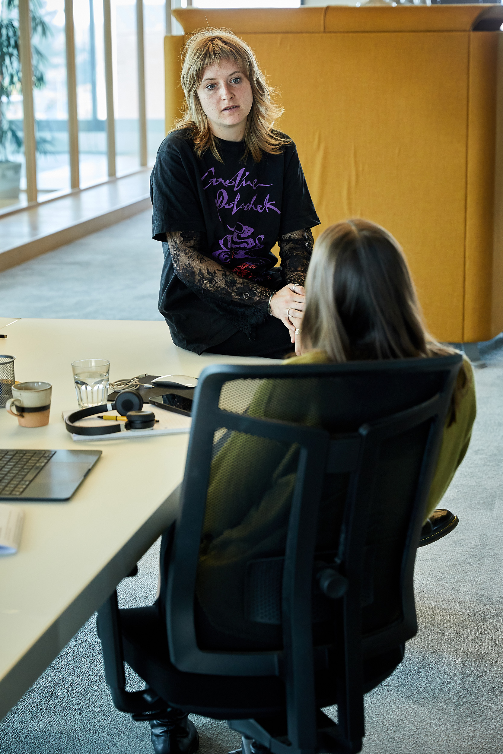 Twee collega's in gesprek aan een bureau.