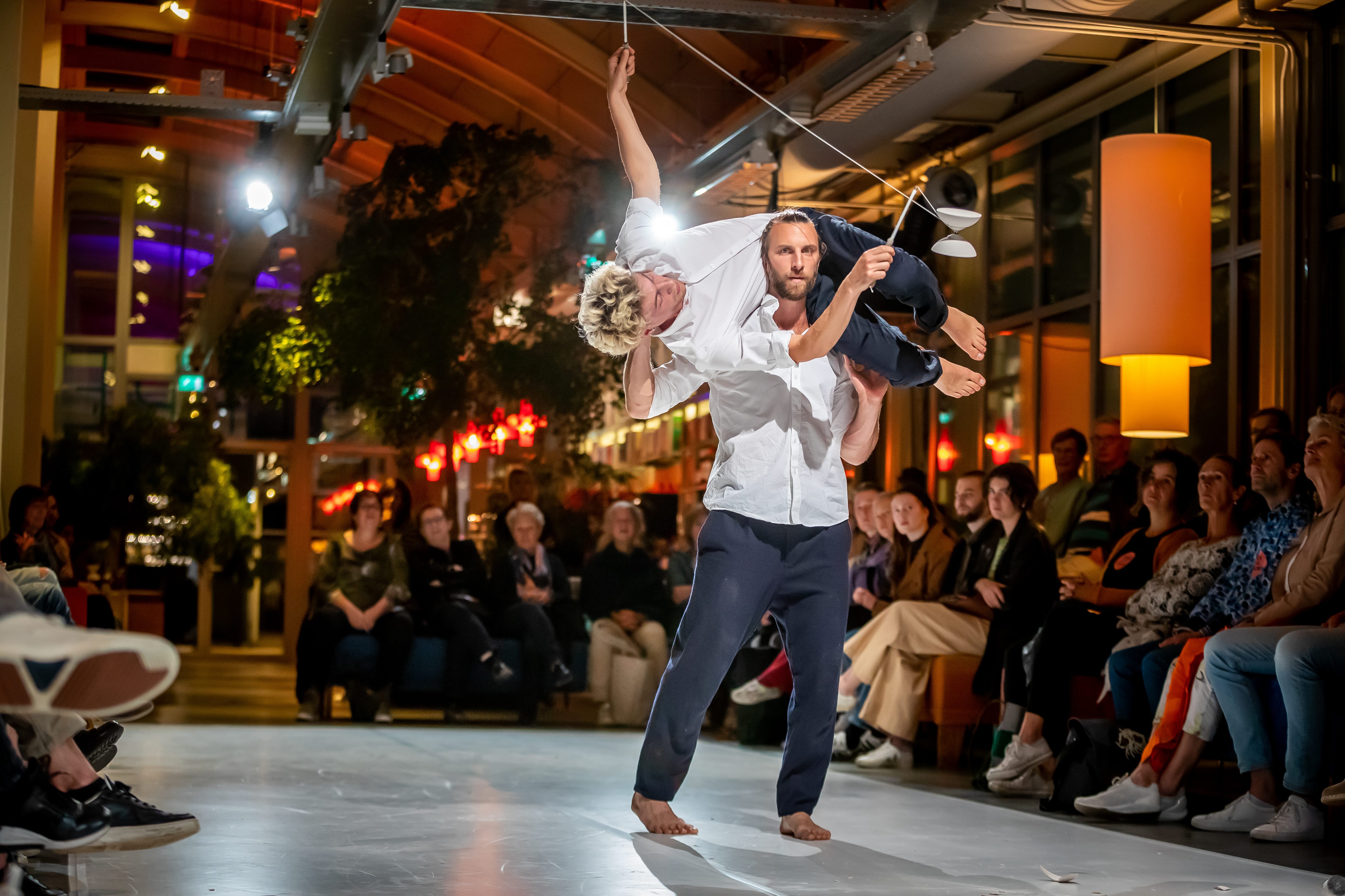Een man ligt tijdens een dansvoorstelling in de nek van de andere en speelt met een diabolo.