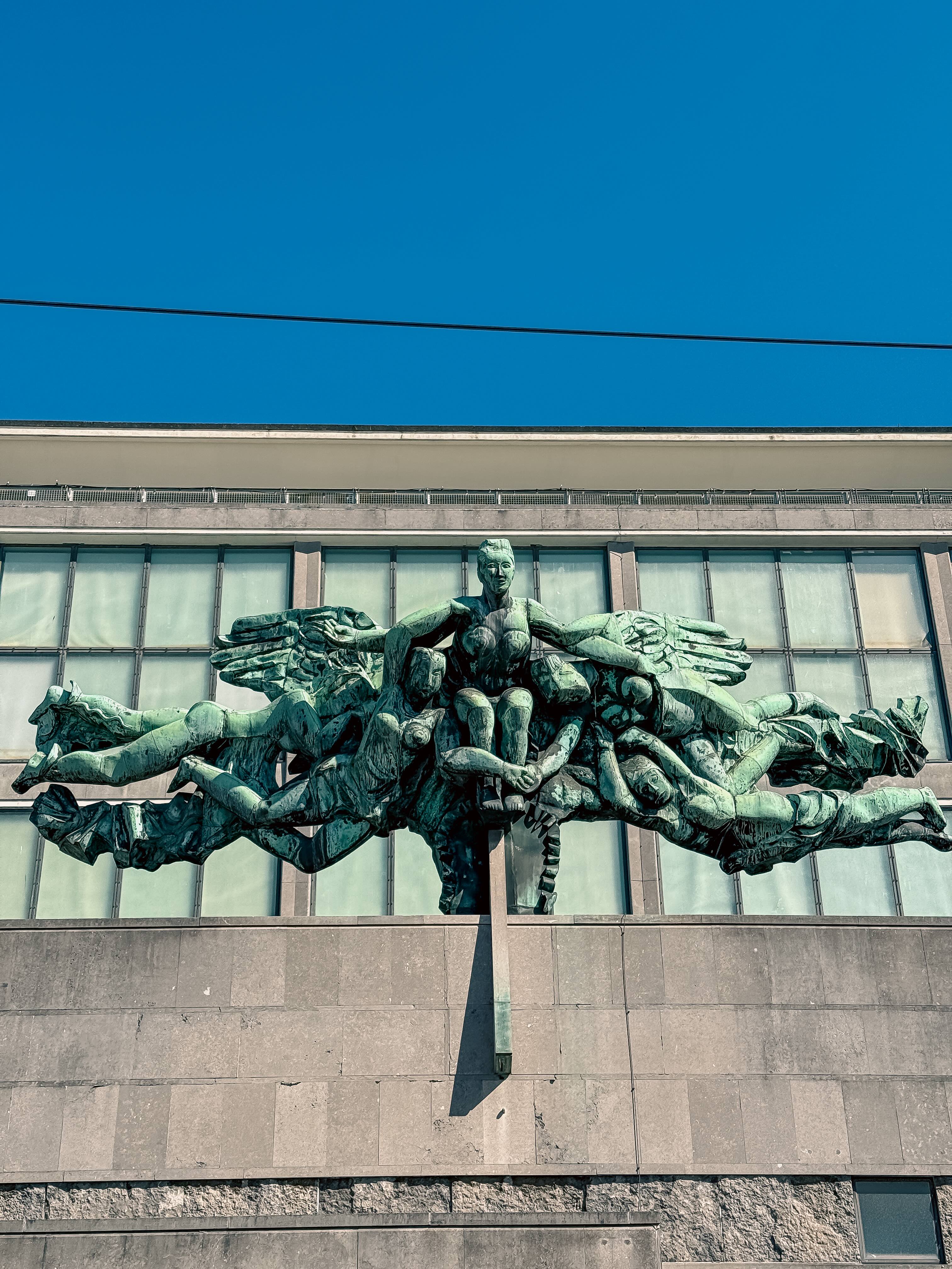 De voorgevel van cultuurcentrum De Grote Post in Oostende, met een indrukwekkend vergroend koperen beeld