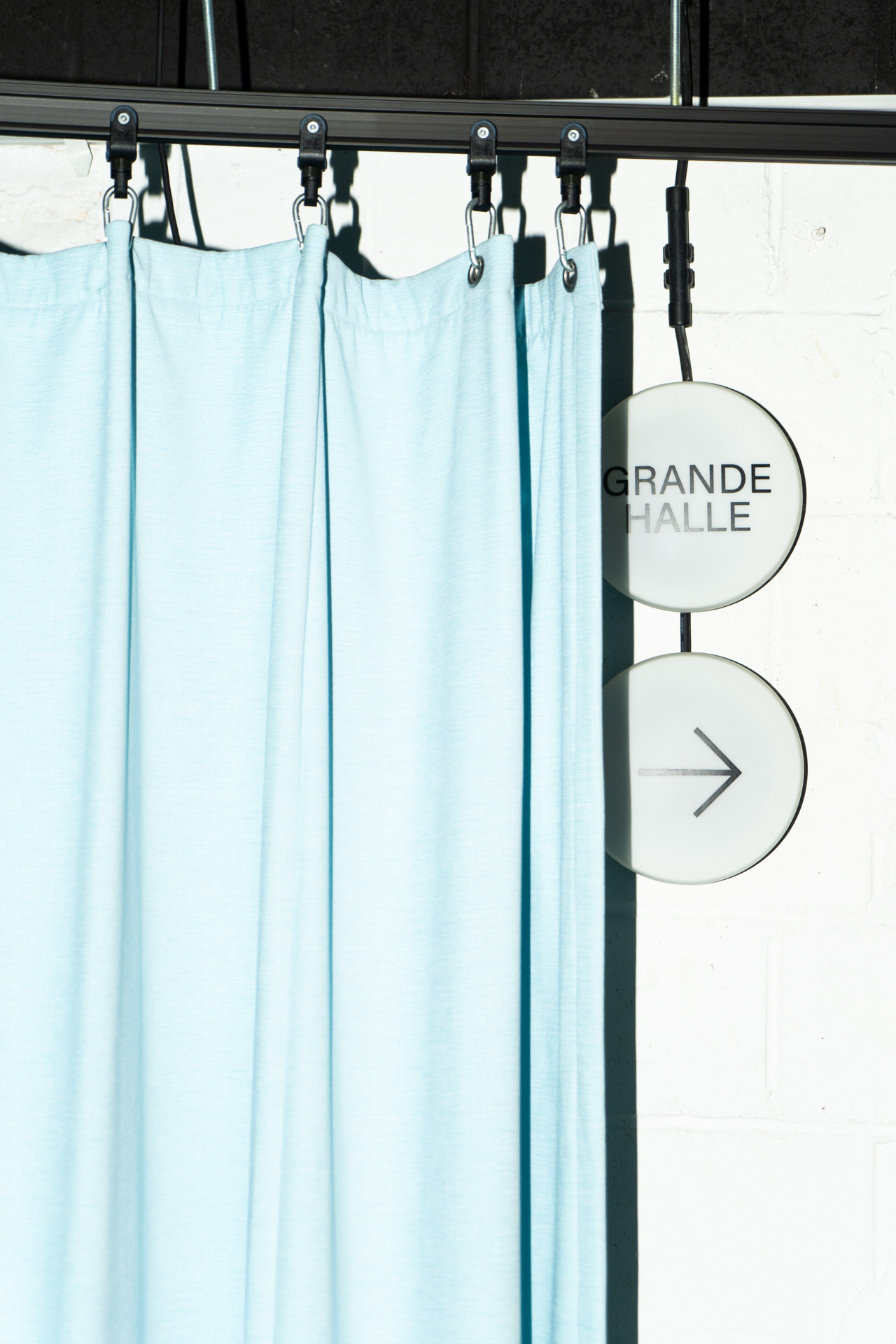 Sign pointing to the Grande Halle behind a light blue curtain.