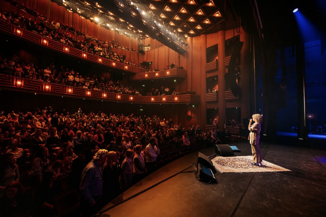 Gevulde theaterzaal van Zwolse theaters met een spreker op het podium