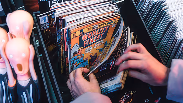 Hands browsing through a rack of comic books with a 'World's Finest' comic visible, next to two scream-like figurines.