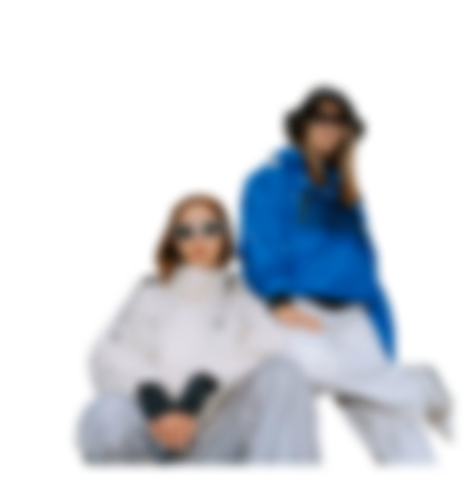 Two women wearing sunglasses and casual jackets, posing together against a plain background.