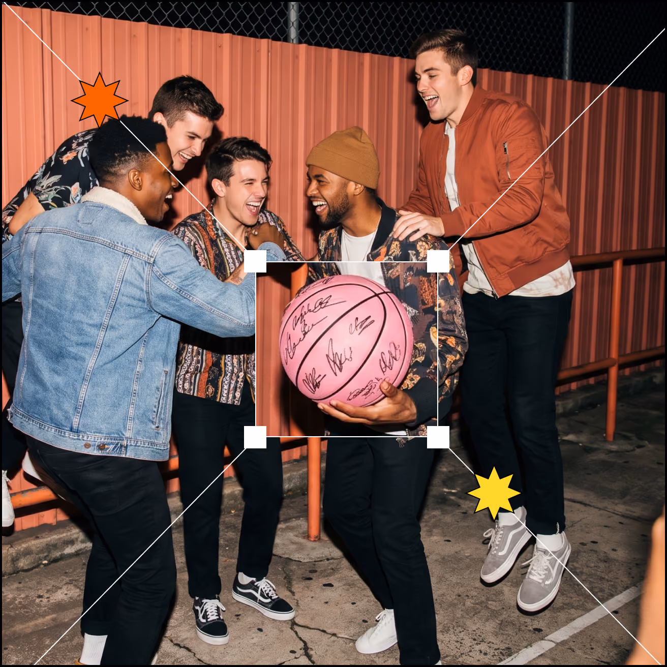 Five men laughing together outdoors at night with one holding a pink basketball signed by multiple people.