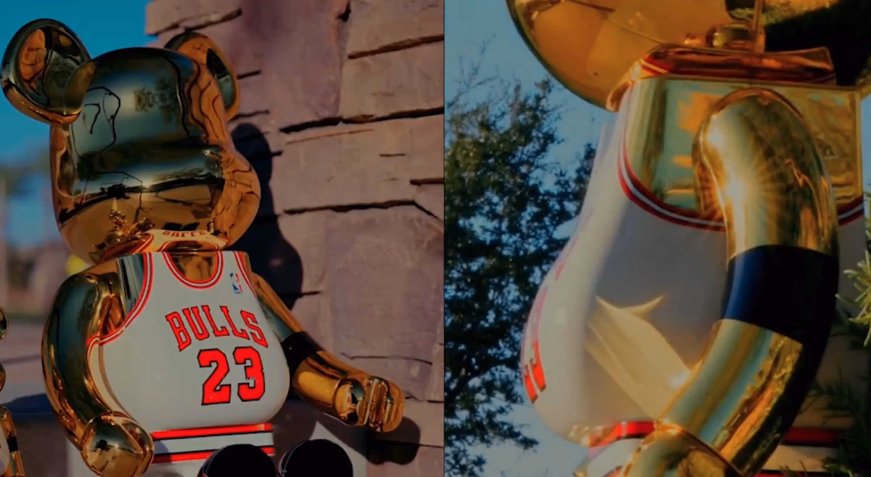 Golden bearbrick figure in a Chicago Bulls 23 basketball jersey outdoors against stone and trees.