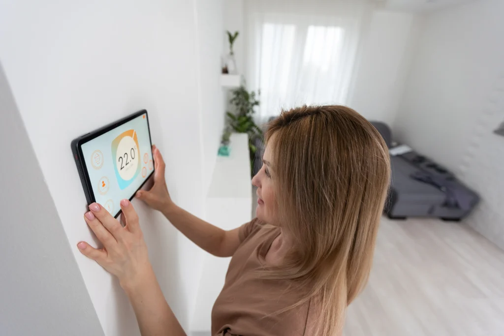 Woman adjusting a smart thermostat on a digital touchscreen in a modern home environment, emphasizing energy-saving temperature control.
