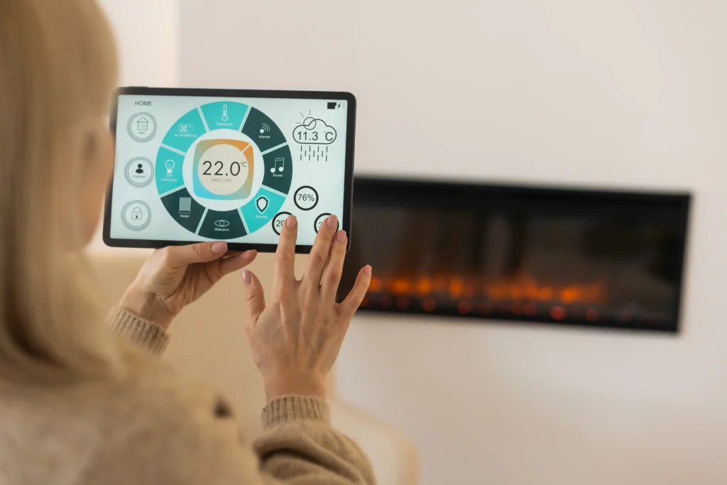 Woman adjusting a digital thermostat on a tablet in a cozy living room with an electric fireplace, emphasizing home heating control and comfort.