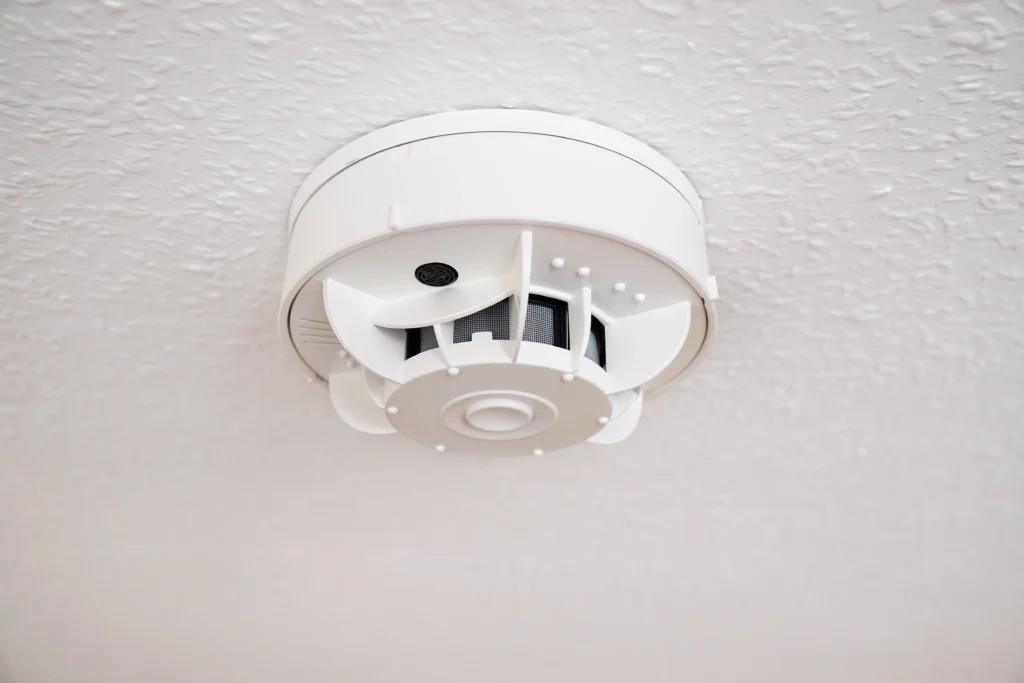 Smoke detector mounted on ceiling, essential for home safety, alerting to carbon monoxide leaks from heating systems.