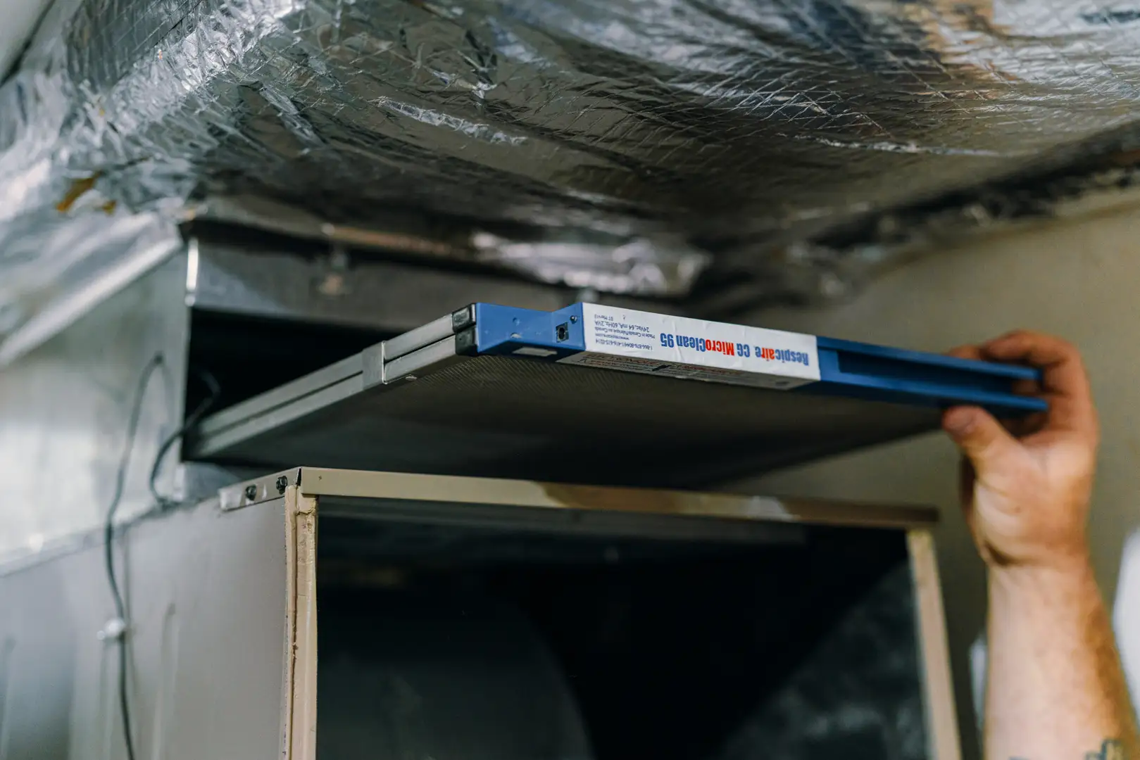 homeowner changing an air filter in a clean utility room - spring ac and hvac maintenance for the south puget sound area