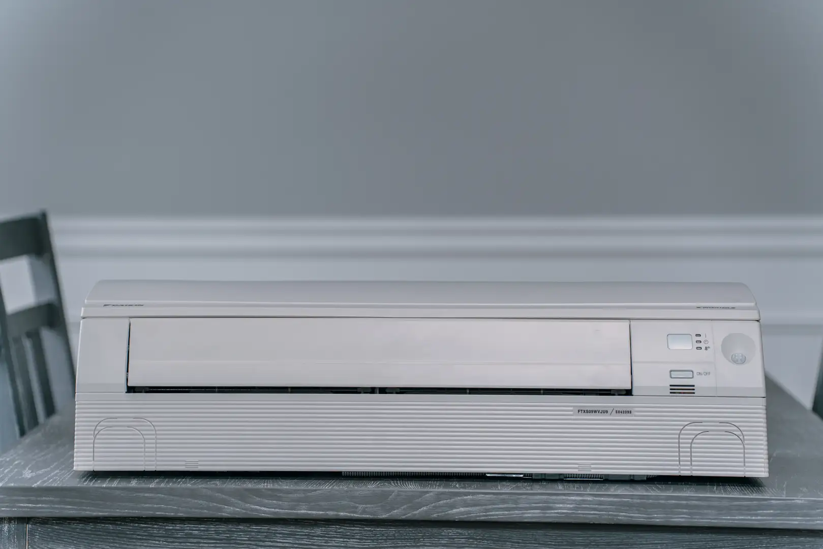 A sleek, modern ductless mini-split indoor unit mounted high on a living room wall - ductless vs central hvac for home A sleek, modern ductless mini-split indoor unit mounted high on a living room wall - ductless vs central hvac for home