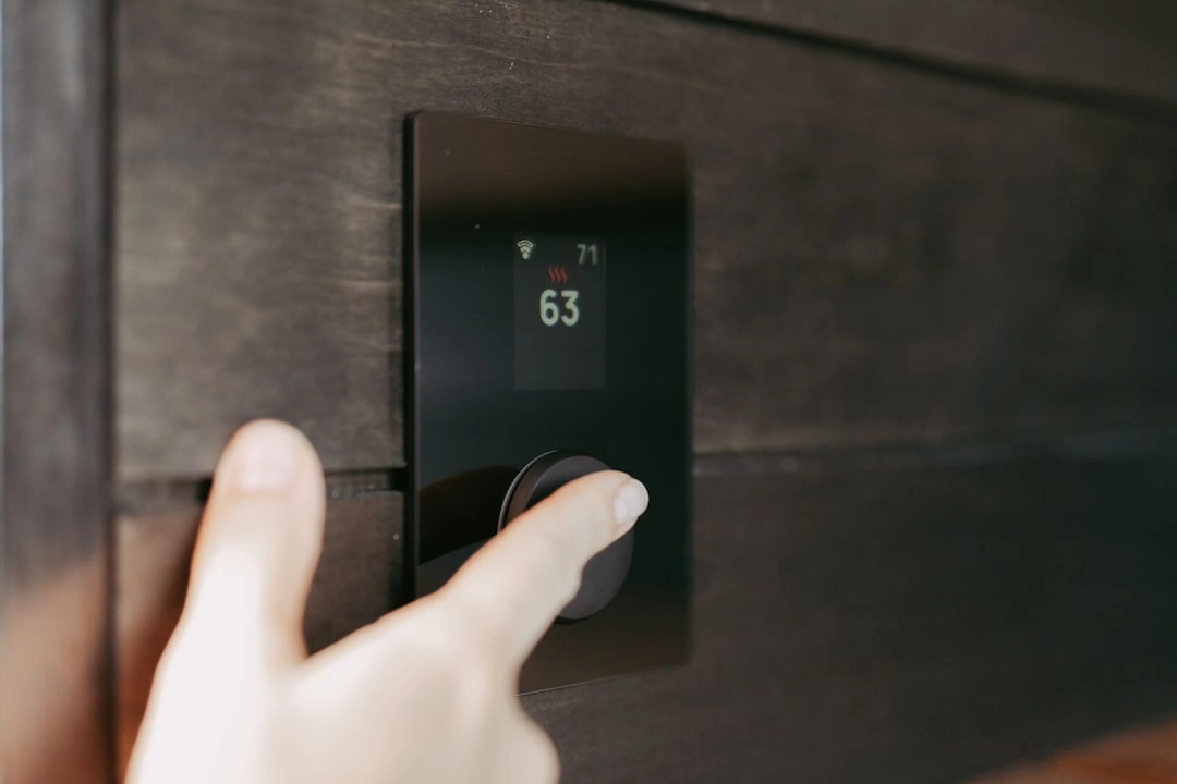 Homeowner adjusting a modern smart thermostat in a well-lit living room - when to repair vs replace your hvac system
