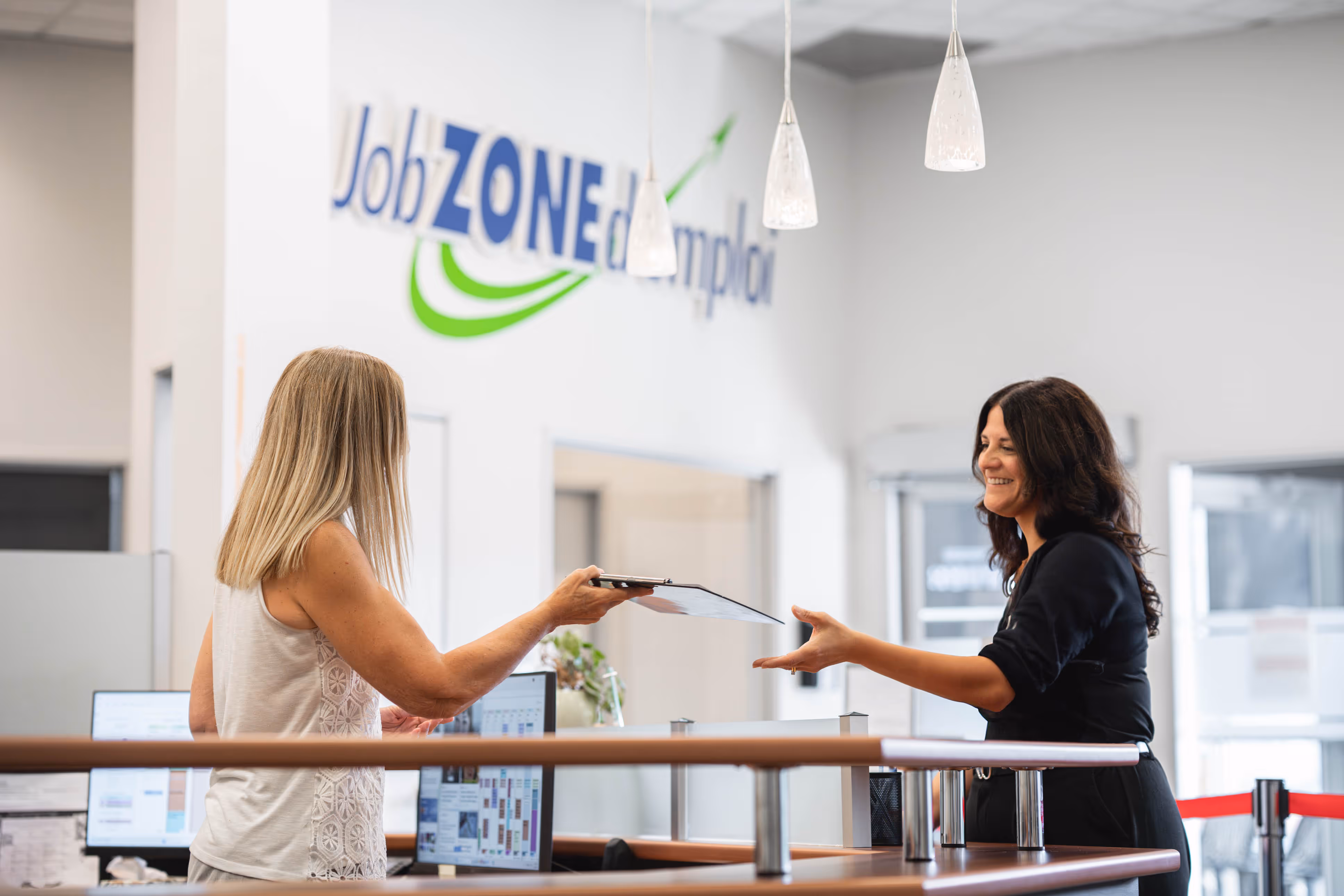 Front receptionist of Job Zone d'emploi handing an application from to a new client