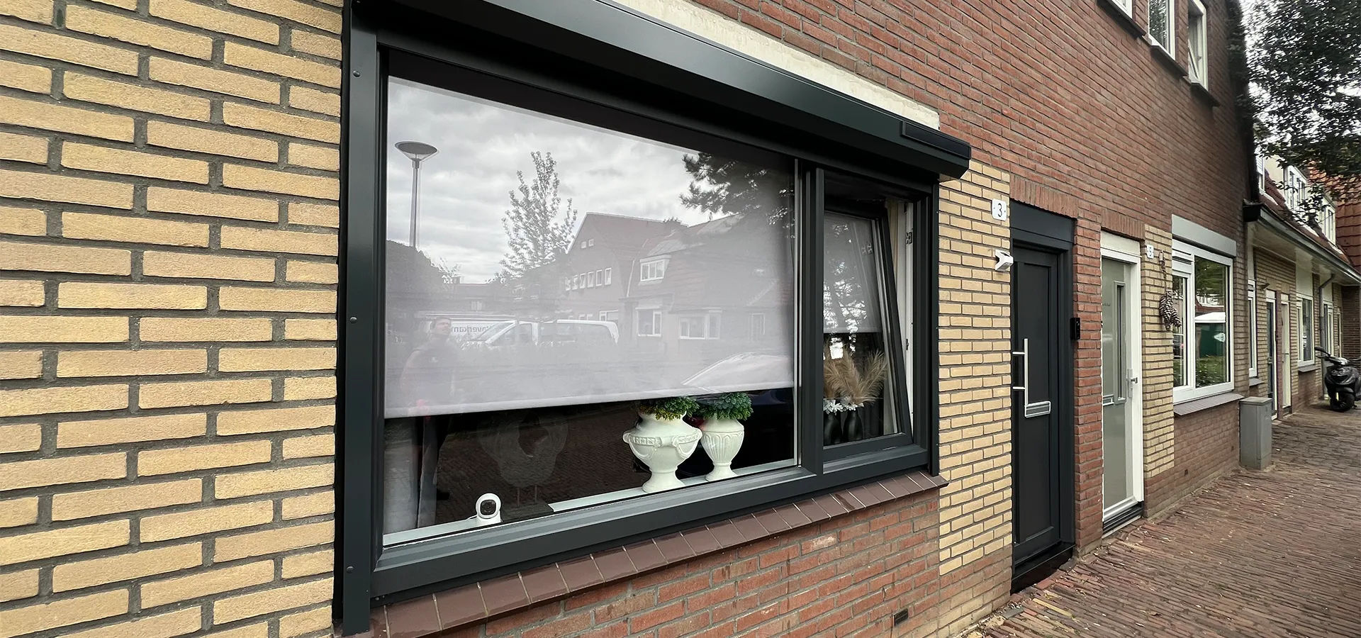 Voorgevel met kunststof kozijnen en voordeur in zwarte afwerking, geplaatst door Brands Kozijnen & Geveltechnieken.