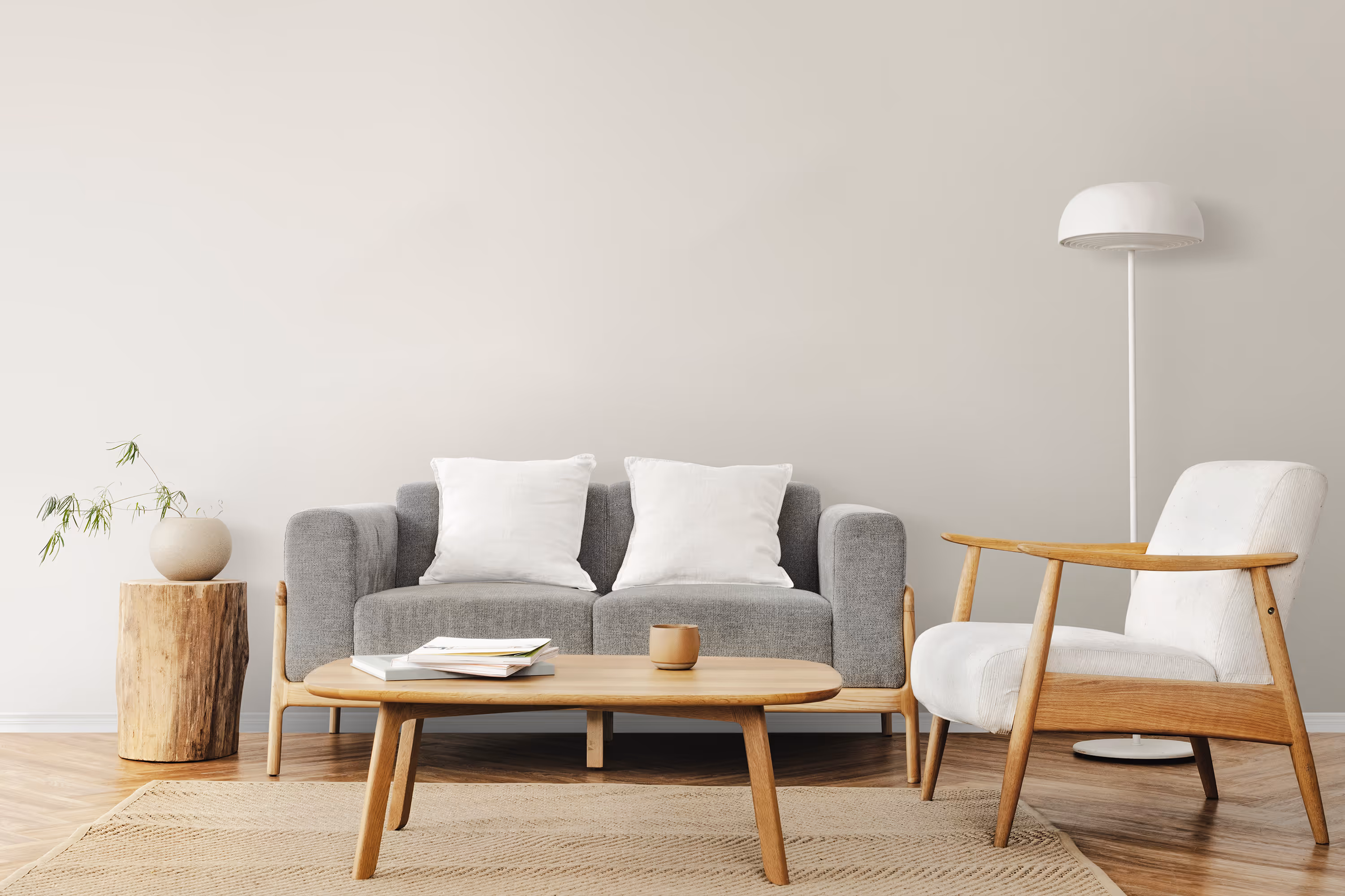 Scandinavian-style living room with grey sofa, white armchair, and wooden coffee table