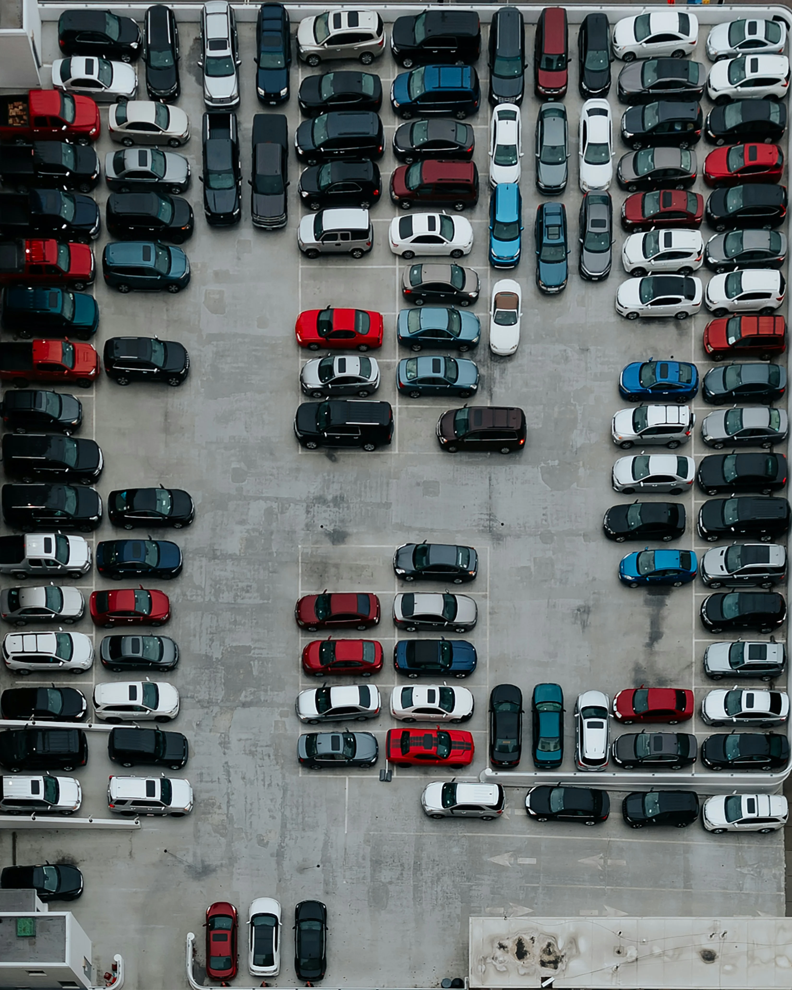 Vista aérea de un estacionamiento con varios coches aparcados en espacios delimitados y algunos espacios vacíos.