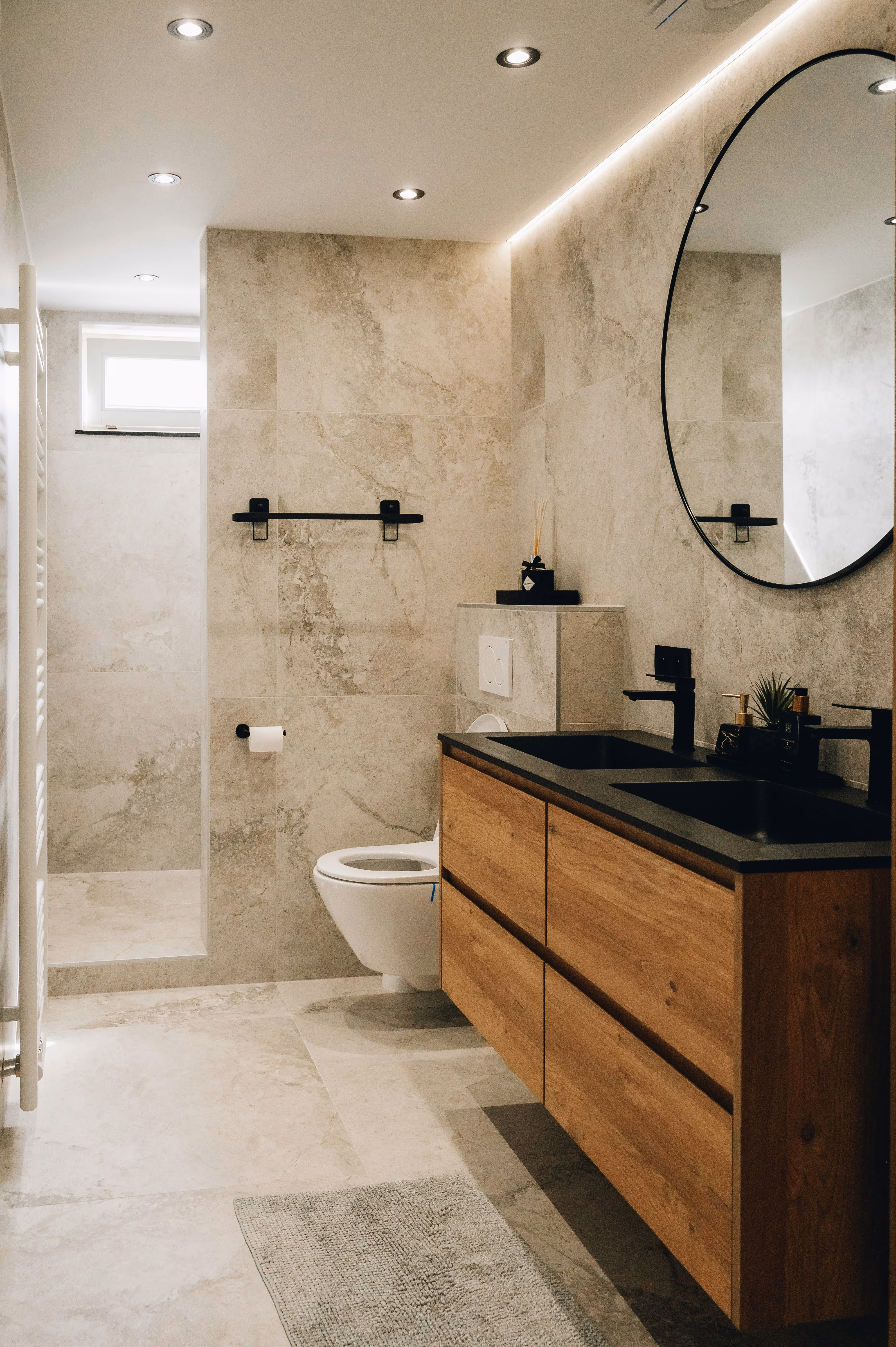 Helles modernes Badezimmer mit rundem Wandspiegel, Holzunterschrank und bodenebener Dusche