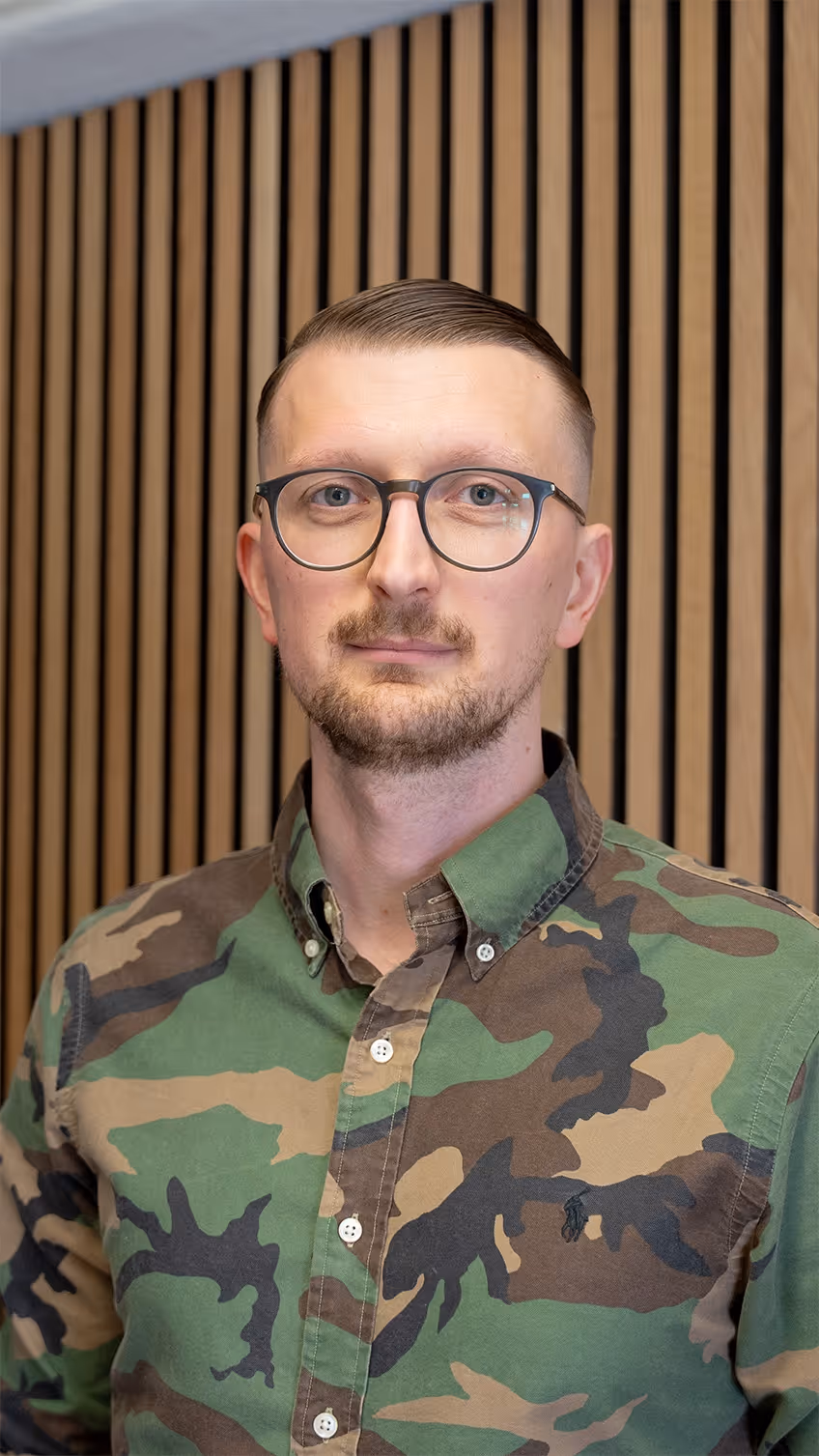 Soldat in Tarnuniform und Brille, Versicherungsmitarbeiter im Hintergrund