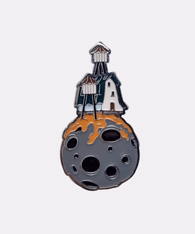Limited edition enamel pin featuring detailed miniature house on a tiny planet, art merchandise by Michael Davydov