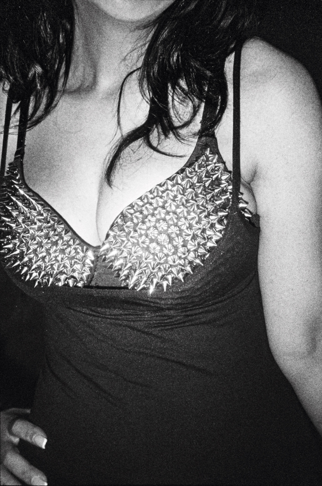 Woman's torso wearing a black top with silver spikes on the chest area and spaghetti straps.