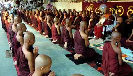 Buddhist monks in maroon robes seated in prayer at a temple in Sri Lanka