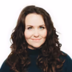 Smiling woman with curly dark hair wearing a black turtleneck against a white background.