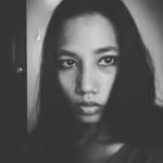 Black and white close-up portrait of a woman with long dark hair and serious expression.