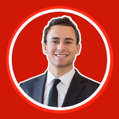 Smiling young man in a black suit and tie with red circular background.