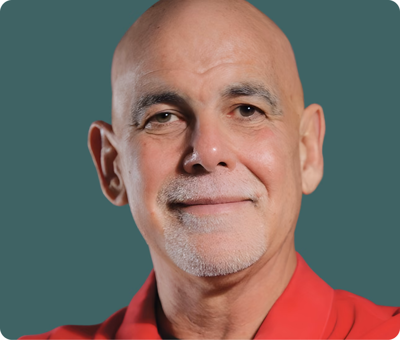 Close-up of a bald middle-aged man with gray goatee wearing a red shirt against a green background.