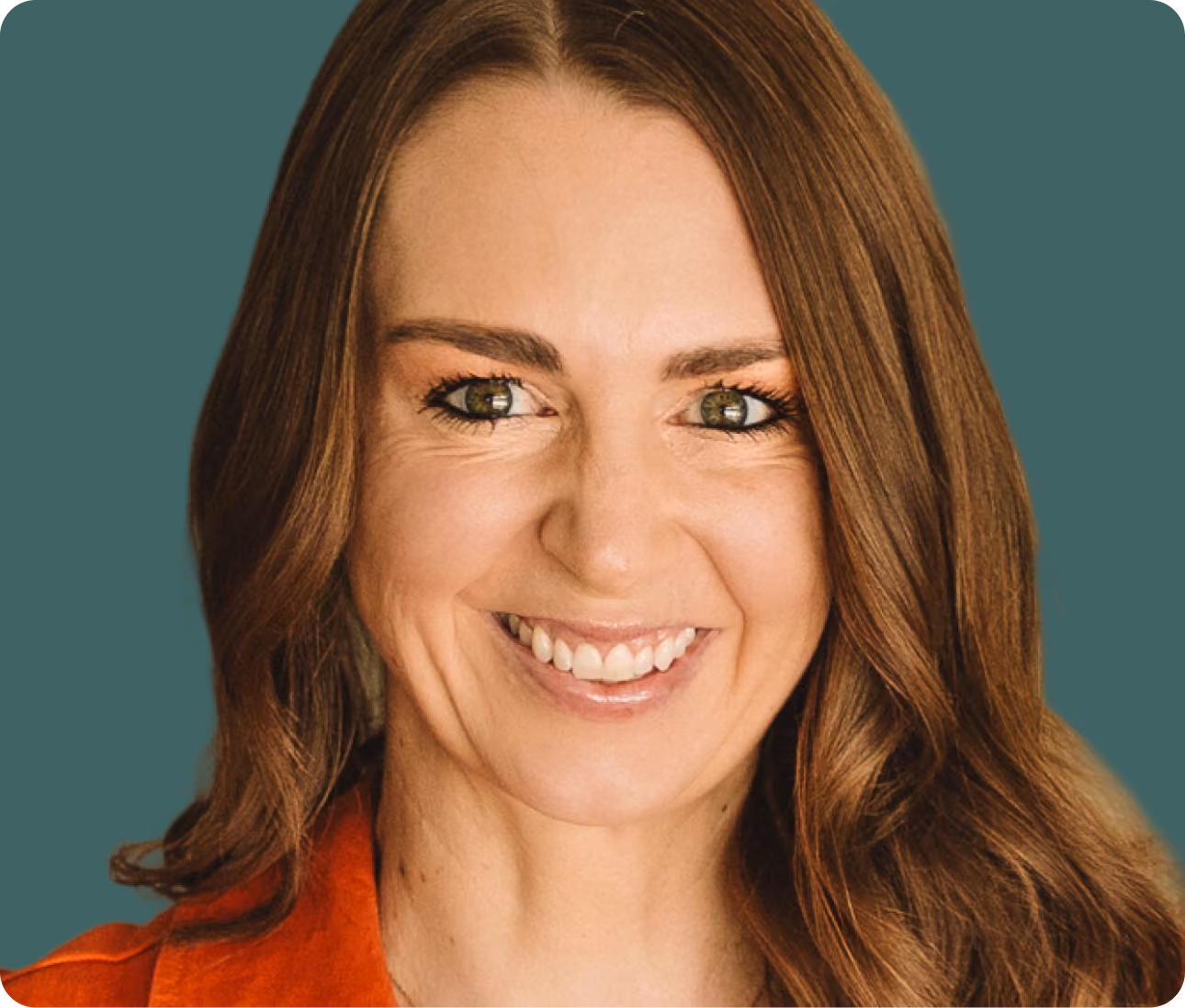 Smiling woman with long brown hair and green eyes wearing an orange top on teal background.