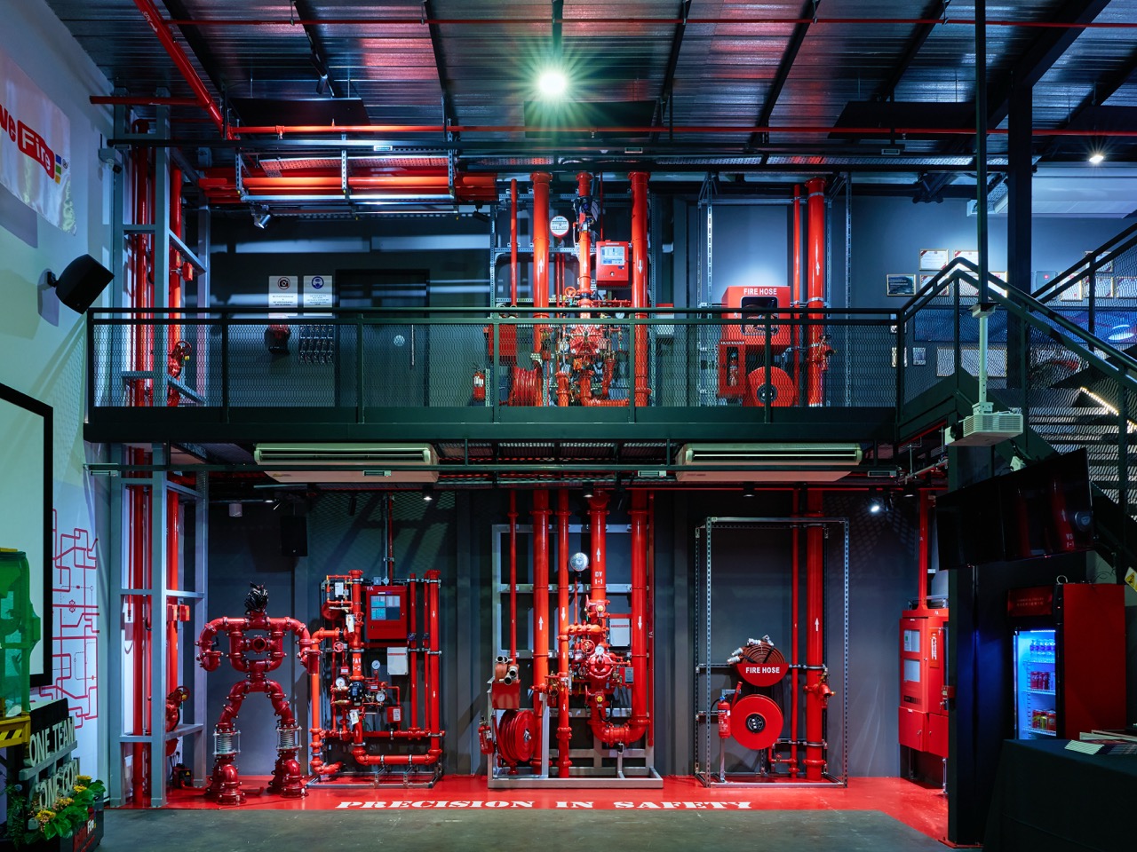 Industrial fire safety system with red pipes, fire hoses, valves, and a metal walkway in a warehouse setting.