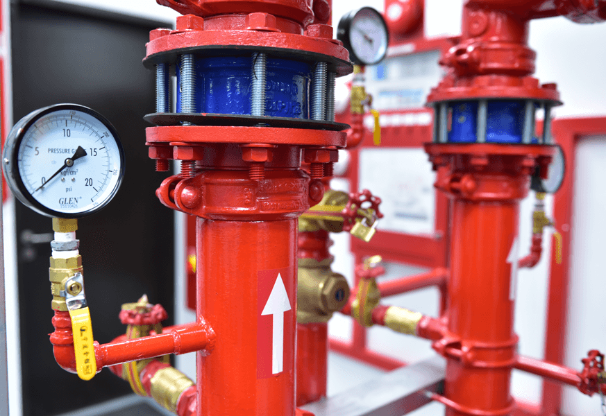 Close-up of red industrial pipes with pressure gauges and valves in a facility.