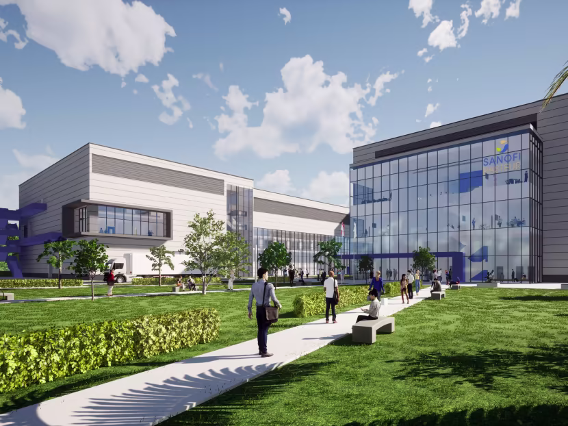 Modern Sanofi facility with glass-front building, green lawn, and people walking on a concrete path under a partly cloudy sky.