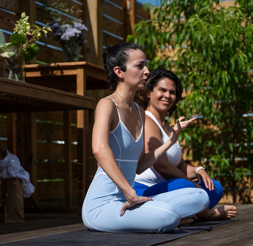 A couple of women sitting on top of a wooden floor.