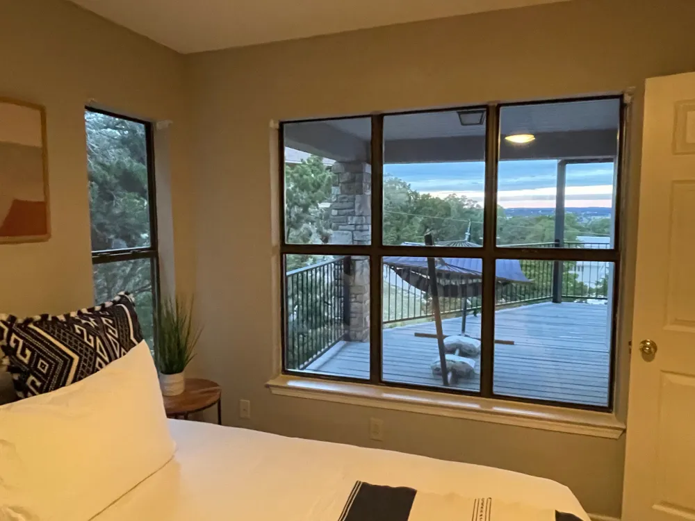 Bedroom with large windows and view of a balcony and hammock.