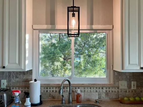 Kitchen sink under window with a tree view.