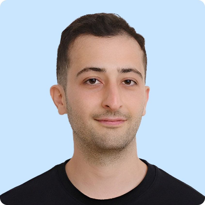 Young man with short dark hair and a slight smile wearing a black shirt against a light purple background.