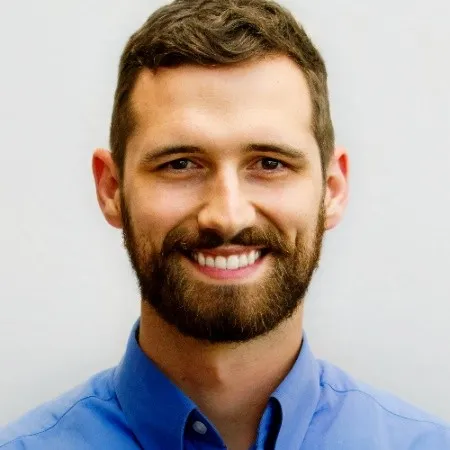 A man with a beard and mustache smiling for a picture.
