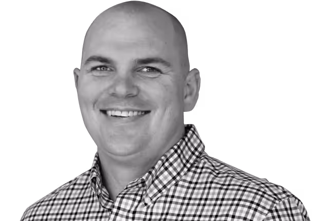 A man with a bald head and a blue plaid shirt smiling.