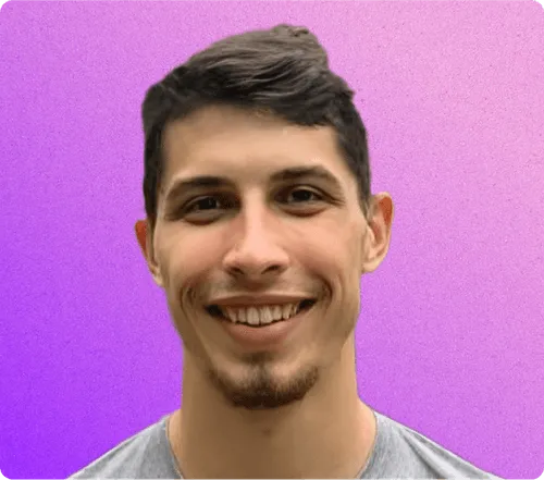Smiling young man with short dark hair and a trimmed beard against a purple gradient background.