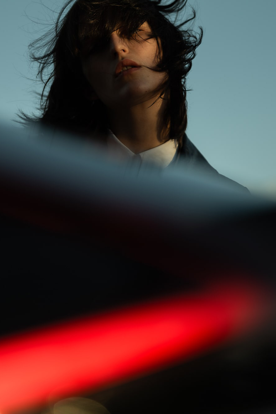 Successful young woman with dark hair in a white business suit looking downwards.