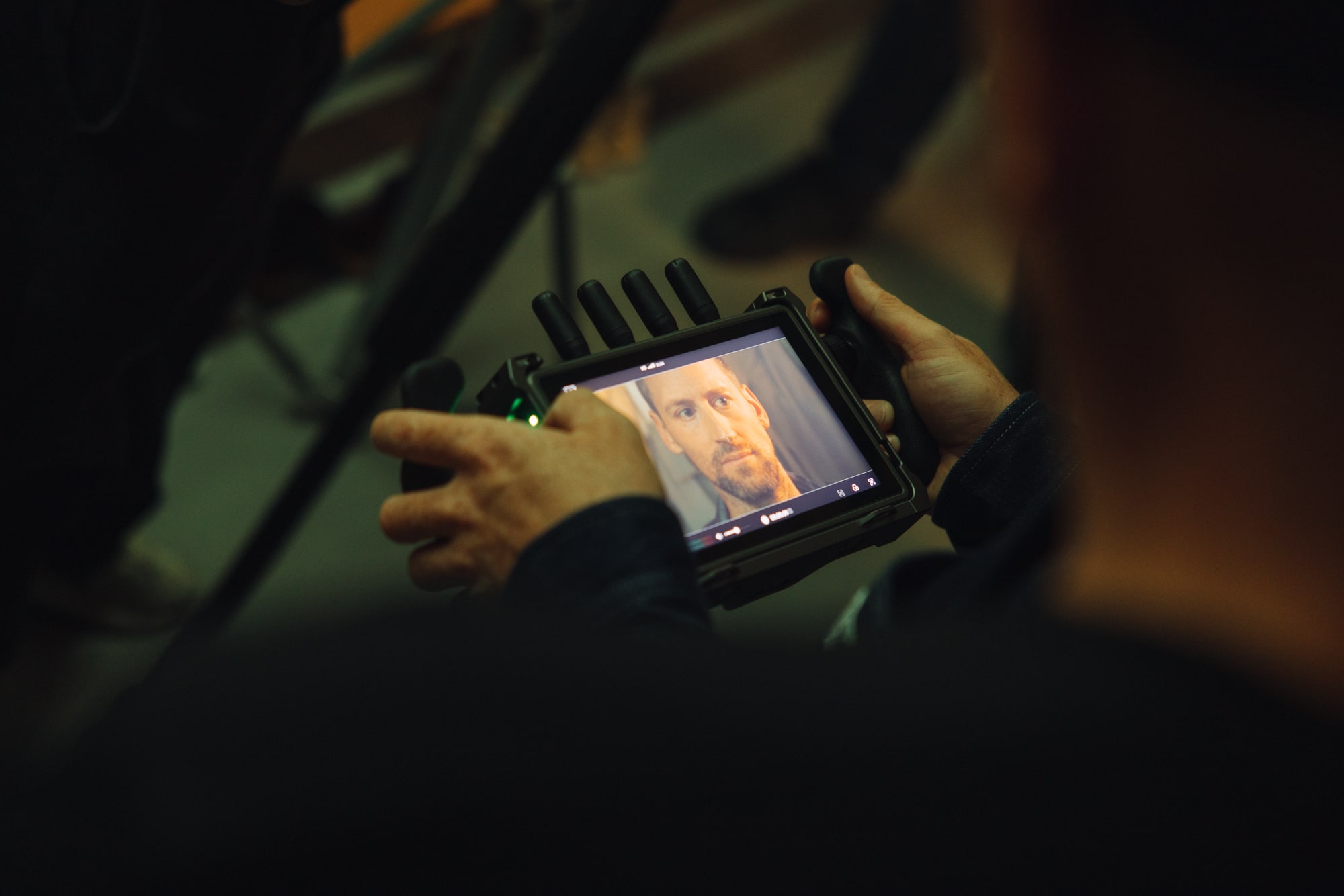 Actor on film set monitoring performance of himself on camera display screen.