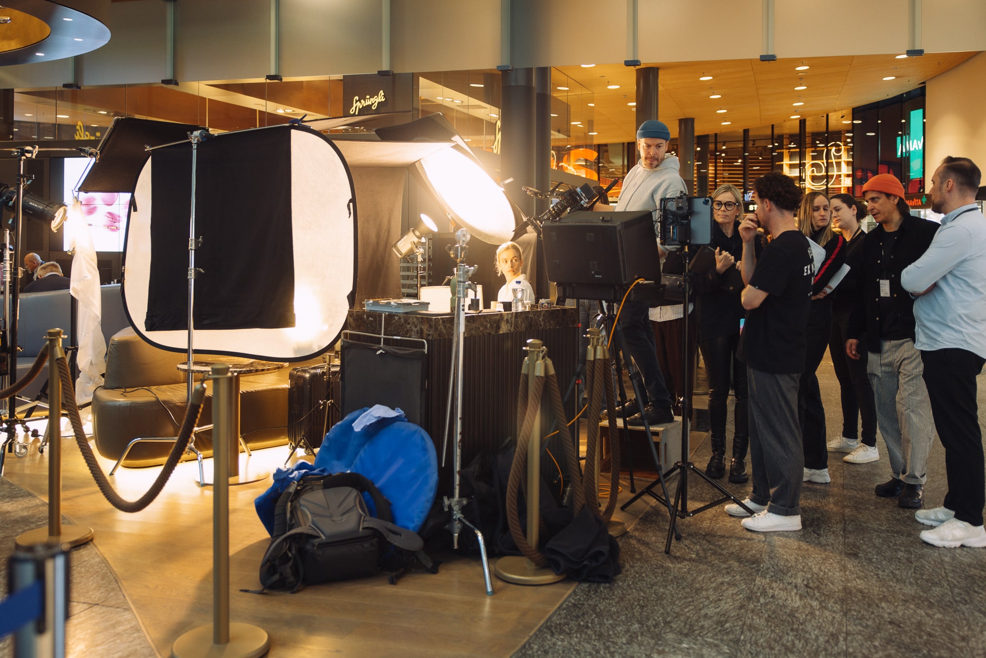 Photography crew captures model in studio setting with professional onlookers and elegant lighting.