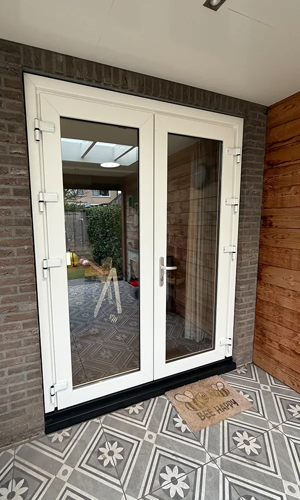 Witte kunststof tuindeuren met grote glaspartijen in bakstenen gevel, onderhoudsarm en strak afgewerkt.